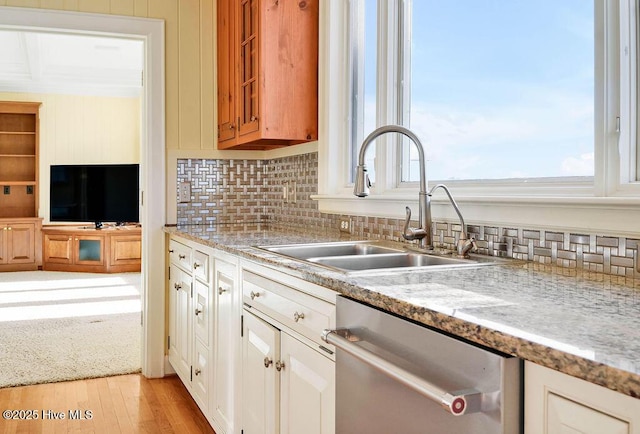 kitchen with stainless steel dishwasher, white cabinetry, sink, and light hardwood / wood-style flooring