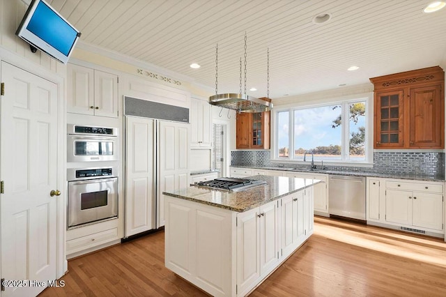 kitchen featuring light stone countertops, a center island, sink, white cabinets, and appliances with stainless steel finishes