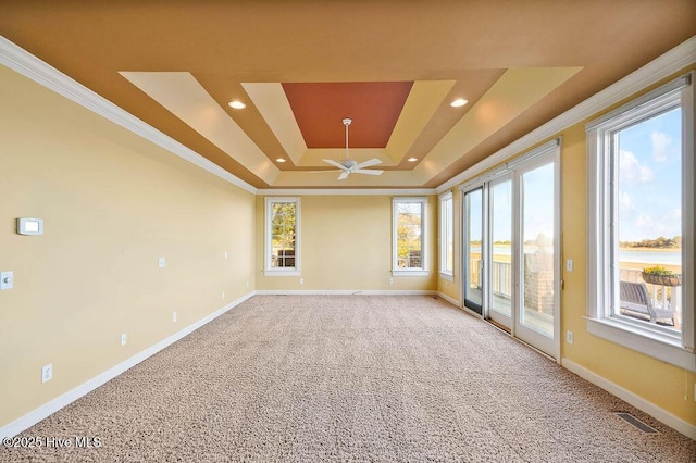 carpeted empty room featuring a wealth of natural light, a tray ceiling, ceiling fan, and ornamental molding