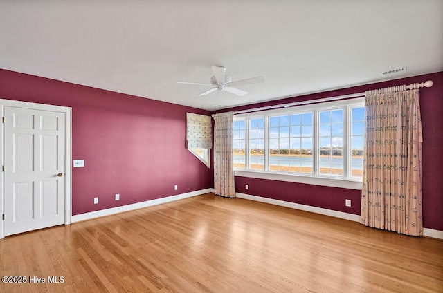 spare room featuring a water view, hardwood / wood-style flooring, and ceiling fan