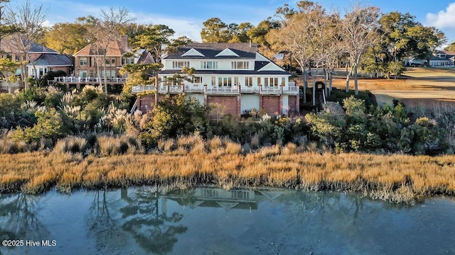 back of property with a balcony and a water view