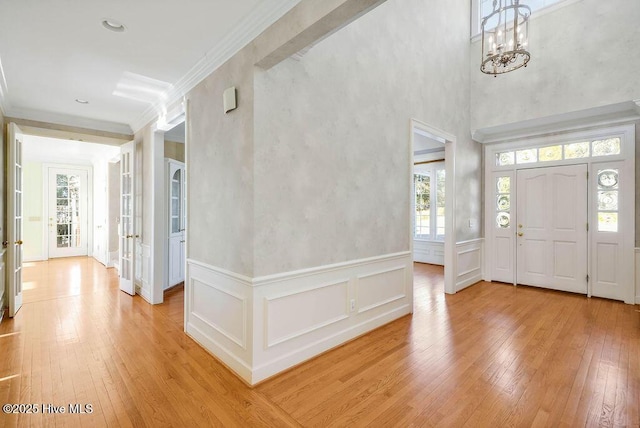 entryway featuring a chandelier, french doors, light hardwood / wood-style floors, and ornamental molding