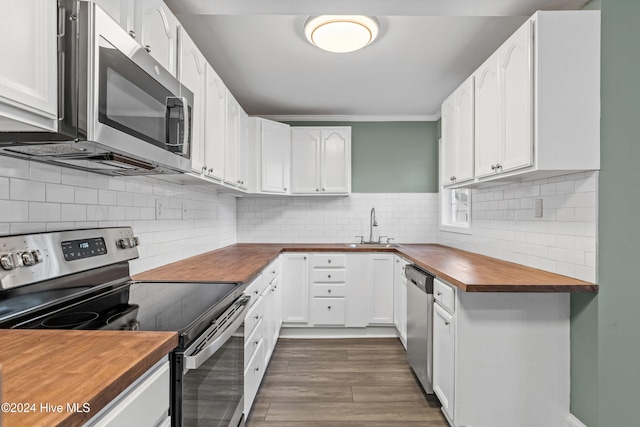 kitchen with dark hardwood / wood-style flooring, white cabinets, stainless steel appliances, and wood counters