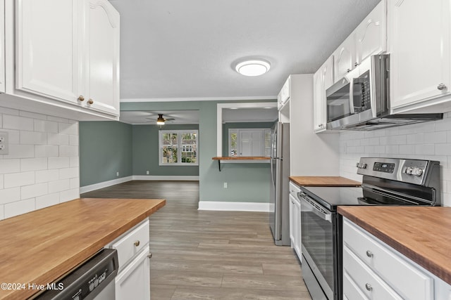 kitchen with white cabinets, wood counters, stainless steel appliances, and tasteful backsplash