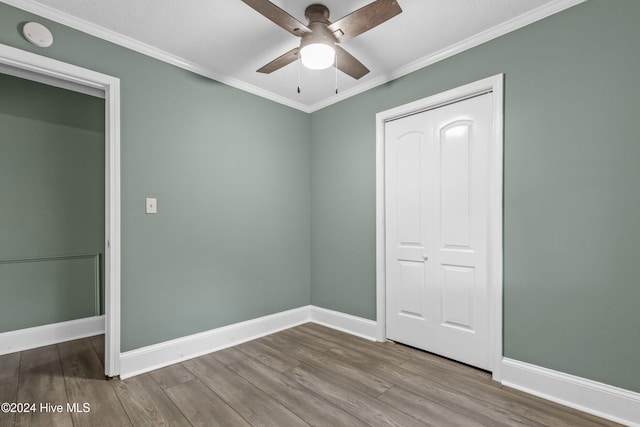 unfurnished bedroom with hardwood / wood-style floors, a closet, ceiling fan, and crown molding