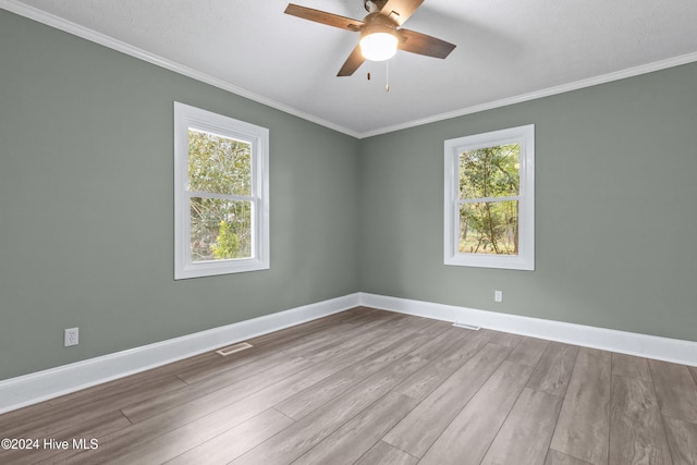 empty room featuring ornamental molding, light hardwood / wood-style flooring, ceiling fan, and a healthy amount of sunlight