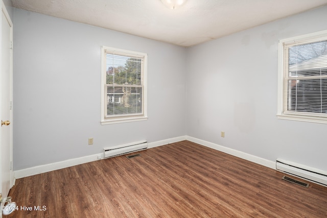 empty room featuring hardwood / wood-style floors and baseboard heating