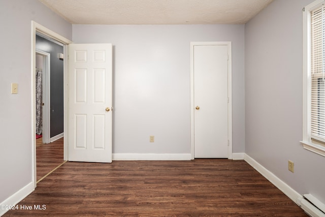 unfurnished bedroom with dark hardwood / wood-style flooring, a textured ceiling, and a baseboard radiator