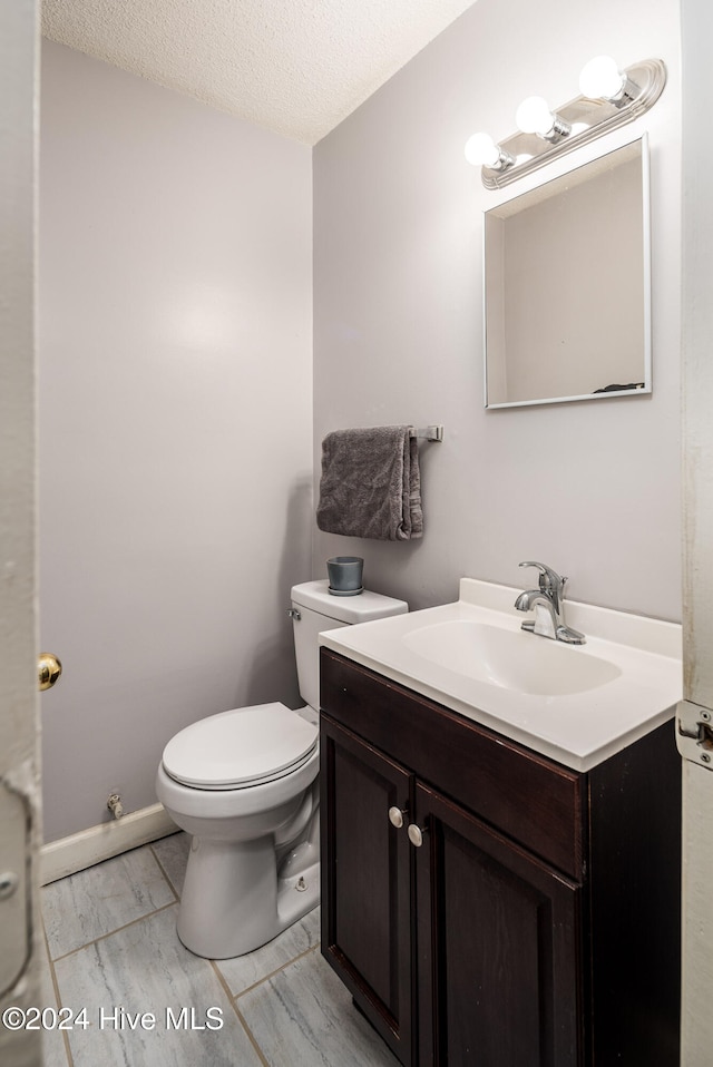 bathroom featuring vanity, a textured ceiling, and toilet