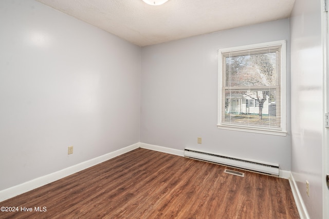 empty room with a textured ceiling, dark hardwood / wood-style flooring, and a baseboard radiator