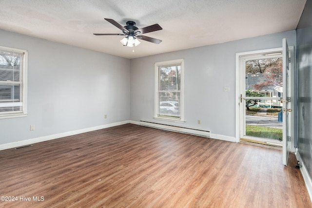 empty room featuring a textured ceiling, light wood-type flooring, ceiling fan, and a baseboard heating unit