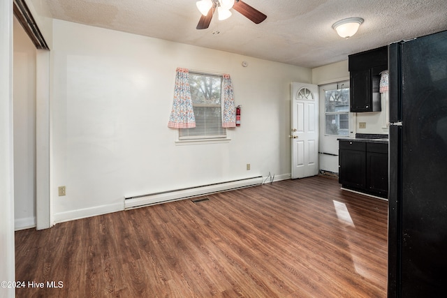 kitchen featuring dark hardwood / wood-style flooring, black fridge, a textured ceiling, and a baseboard heating unit