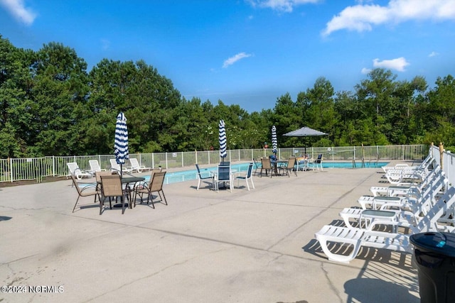 community pool with a patio and fence