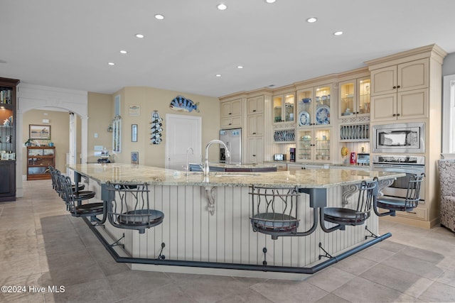 10108 Sea Breeze Dr, Emerald Isle, NC 28594 - kitchen featuring cream cabinets, stainless steel appliances, a kitchen breakfast bar, recessed lighting, and arched walkways