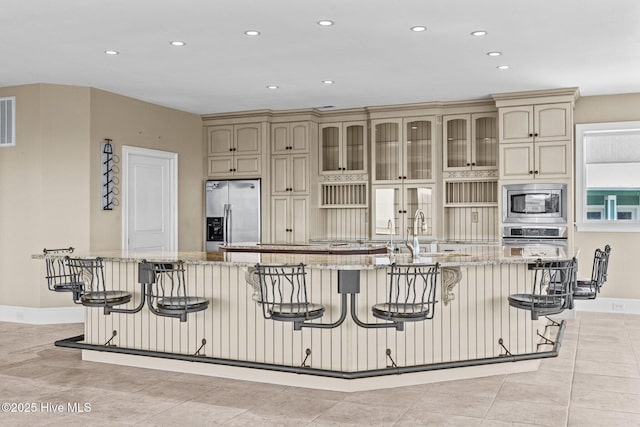 10108 Sea Breeze Dr, Emerald Isle, NC 28594 - kitchen with appliances with stainless steel finishes, cream cabinetry, recessed lighting, a spacious island, and light stone countertops