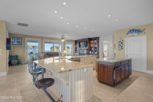 kitchen featuring sink, stainless steel dishwasher, an island with sink, dark brown cabinetry, and a breakfast bar area