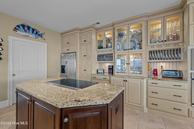 kitchen with black electric cooktop, cream cabinets, a center island, and stainless steel refrigerator with ice dispenser