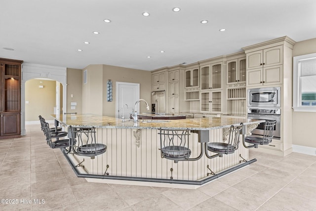 10108 Sea Breeze Dr, Emerald Isle, NC 28594 - kitchen with cream cabinetry, stainless steel appliances, recessed lighting, arched walkways, and a breakfast bar area