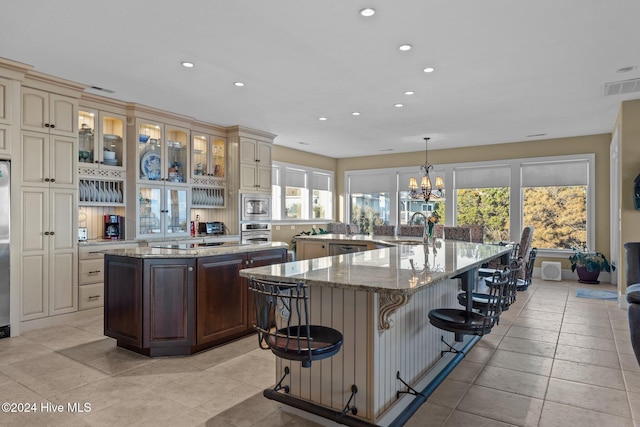 kitchen featuring a kitchen bar, appliances with stainless steel finishes, sink, cream cabinets, and decorative light fixtures