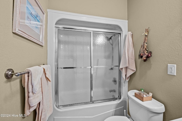 bathroom featuring toilet and bath / shower combo with glass door