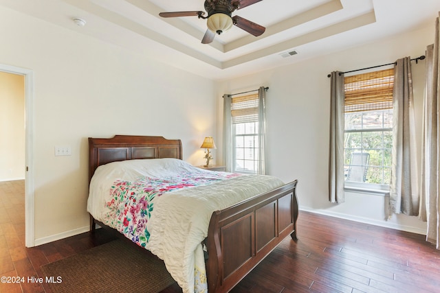 bedroom featuring dark hardwood / wood-style flooring, a raised ceiling, and ceiling fan