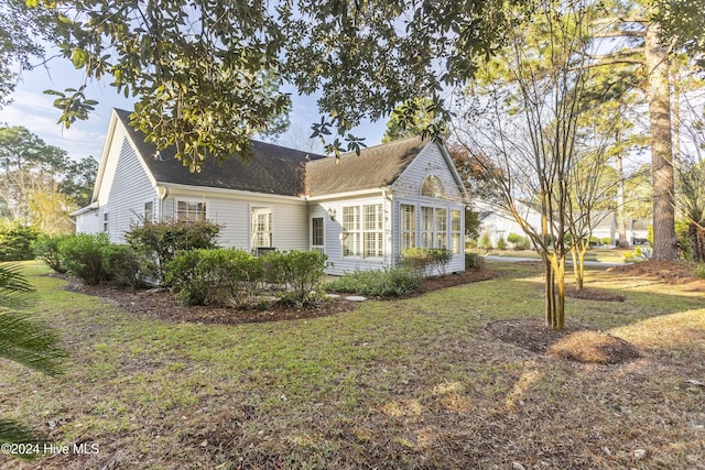 864 Sandpiper Bay Dr SW, Sunset Beach, NC 28468 - view of home's exterior featuring a yard, a shingled roof, and a sunroom