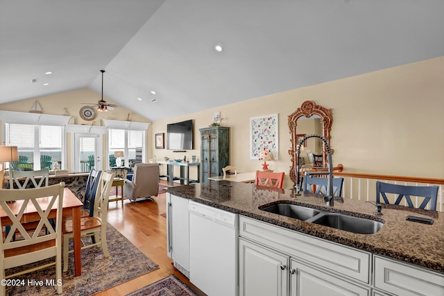 kitchen featuring light wood-type flooring, white dishwasher, dark stone countertops, white cabinetry, and lofted ceiling