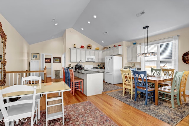 dining space with sink, high vaulted ceiling, and light hardwood / wood-style floors