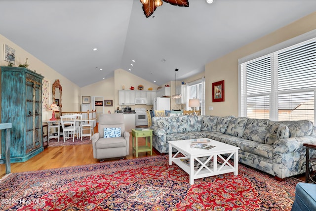 living room featuring light hardwood / wood-style flooring, vaulted ceiling, and ceiling fan