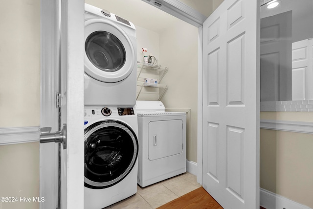 laundry room featuring light tile patterned floors and stacked washer / dryer