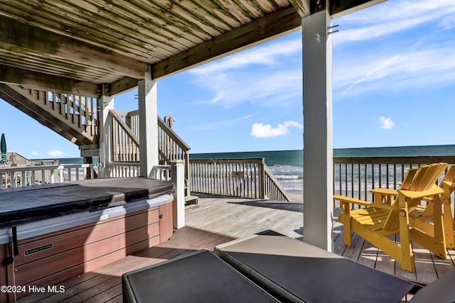 deck featuring a beach view, a water view, and a hot tub