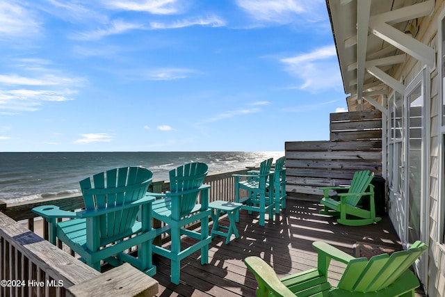 wooden terrace featuring a water view and a view of the beach