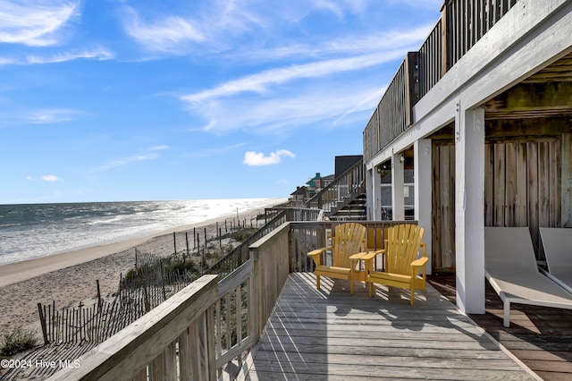 exterior space featuring a deck with water view and a beach view