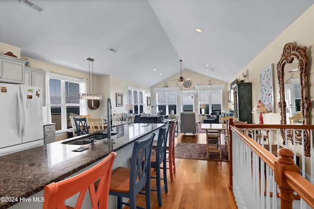 kitchen with pendant lighting, lofted ceiling, white refrigerator, and light hardwood / wood-style floors