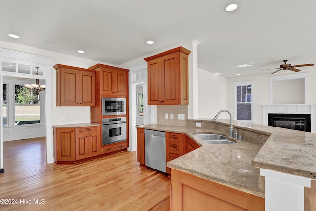 kitchen with sink, kitchen peninsula, stainless steel appliances, and light hardwood / wood-style flooring