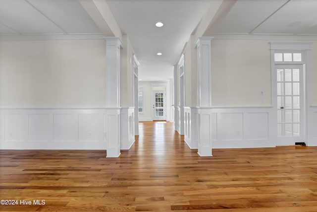 corridor with ornate columns, crown molding, and light hardwood / wood-style flooring