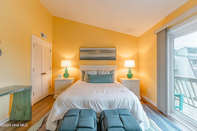 bedroom with access to exterior, light hardwood / wood-style flooring, vaulted ceiling, and a closet