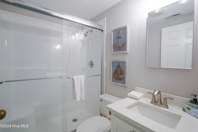 bathroom with a shower with door, vanity, and toilet