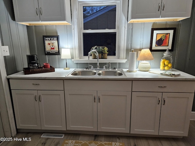 bar featuring visible vents, a sink, and wood finished floors