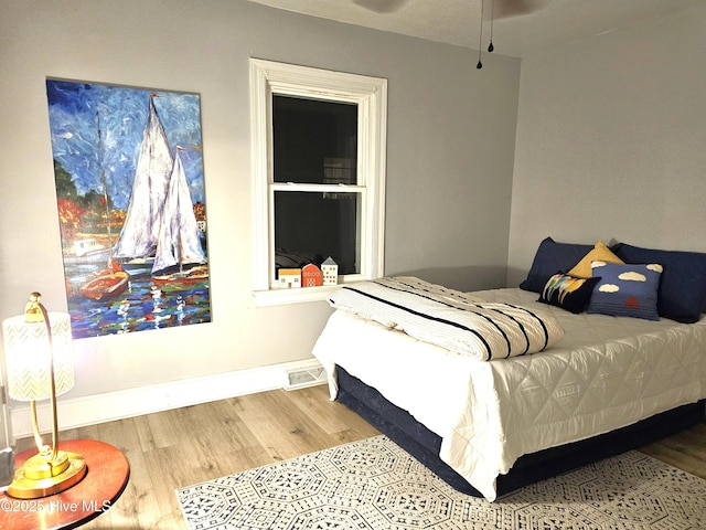 bedroom featuring visible vents, baseboards, and wood finished floors