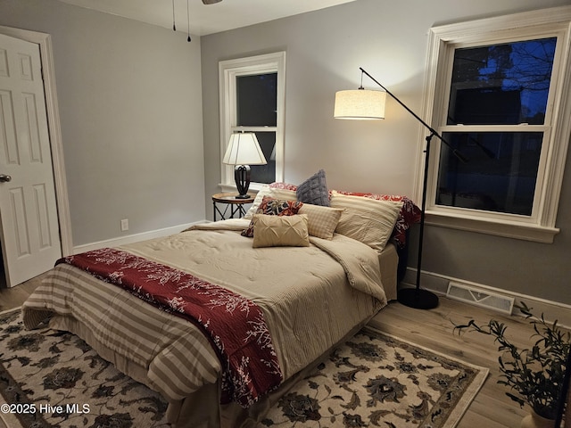 bedroom featuring visible vents, baseboards, and wood finished floors