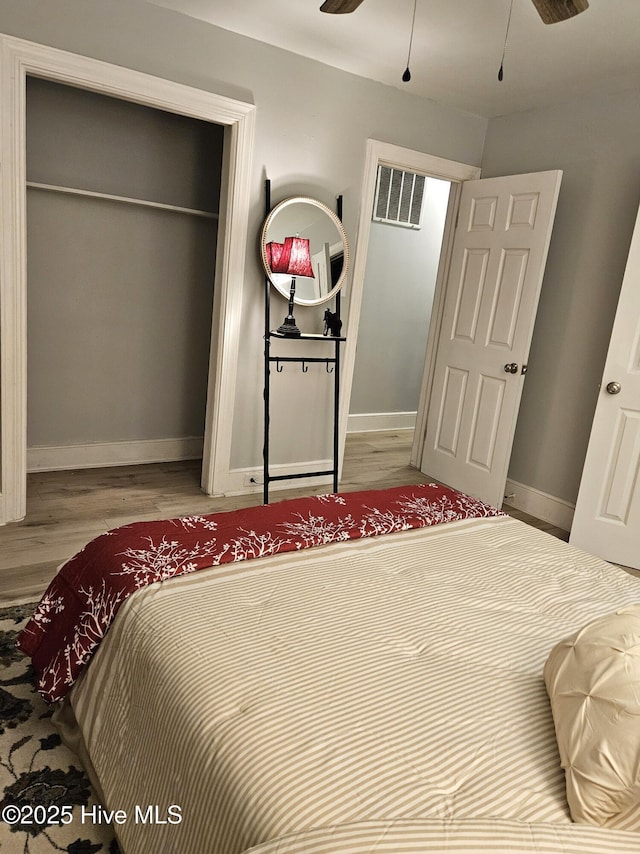 bedroom featuring baseboards, a closet, visible vents, and wood finished floors