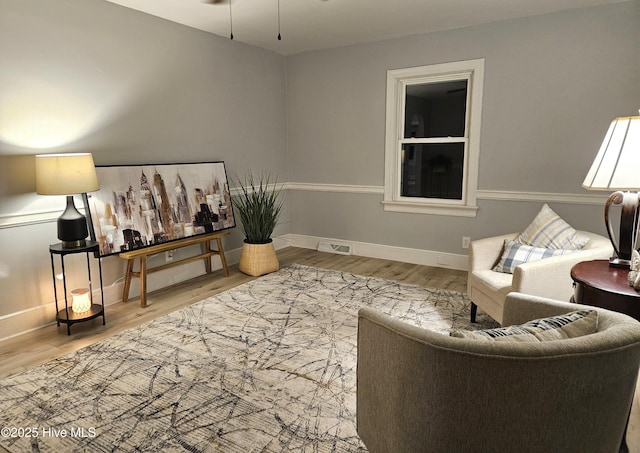 sitting room featuring baseboards, visible vents, and wood finished floors