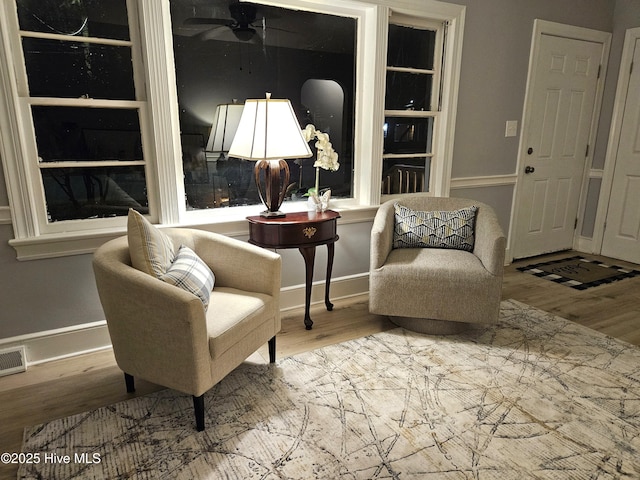 sitting room with ceiling fan, baseboards, and wood finished floors