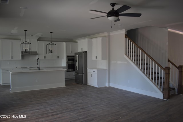 kitchen featuring appliances with stainless steel finishes, white cabinetry, hanging light fixtures, ceiling fan, and a center island with sink