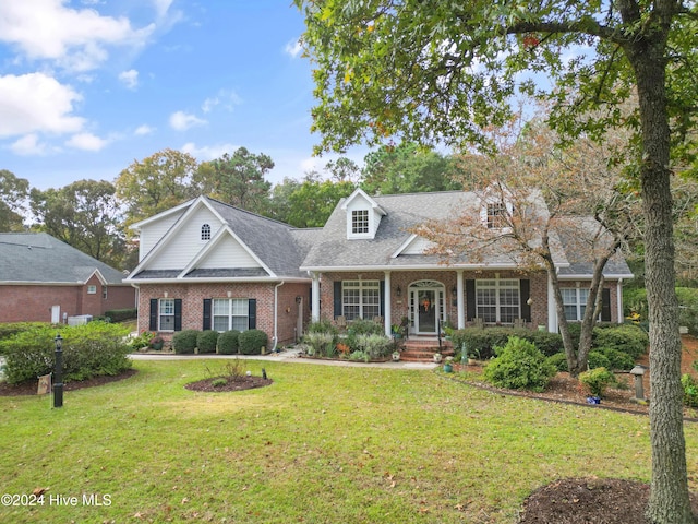 cape cod-style house featuring covered porch and a front lawn