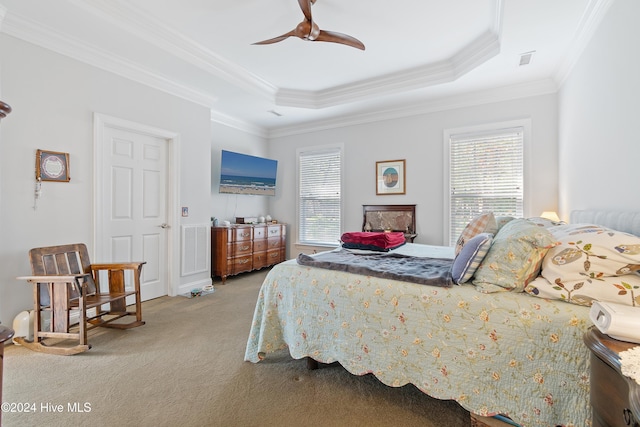 carpeted bedroom featuring a tray ceiling, ceiling fan, and ornamental molding