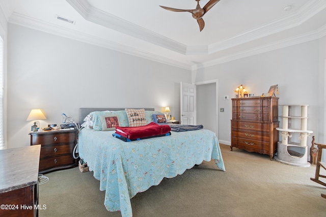 carpeted bedroom with a raised ceiling, ceiling fan, and ornamental molding