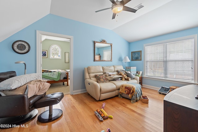 living room with a wealth of natural light, ceiling fan, light hardwood / wood-style floors, and vaulted ceiling