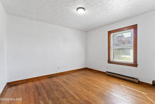 spare room with a baseboard radiator, a textured ceiling, and light hardwood / wood-style floors